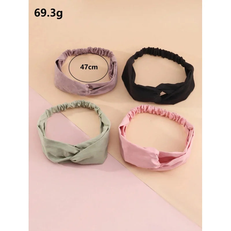 Ein Set aus vier weichen Stoff-Headbands in Lavendel, Schwarz, Salbeigrün und Pink auf hellem Hintergrund.