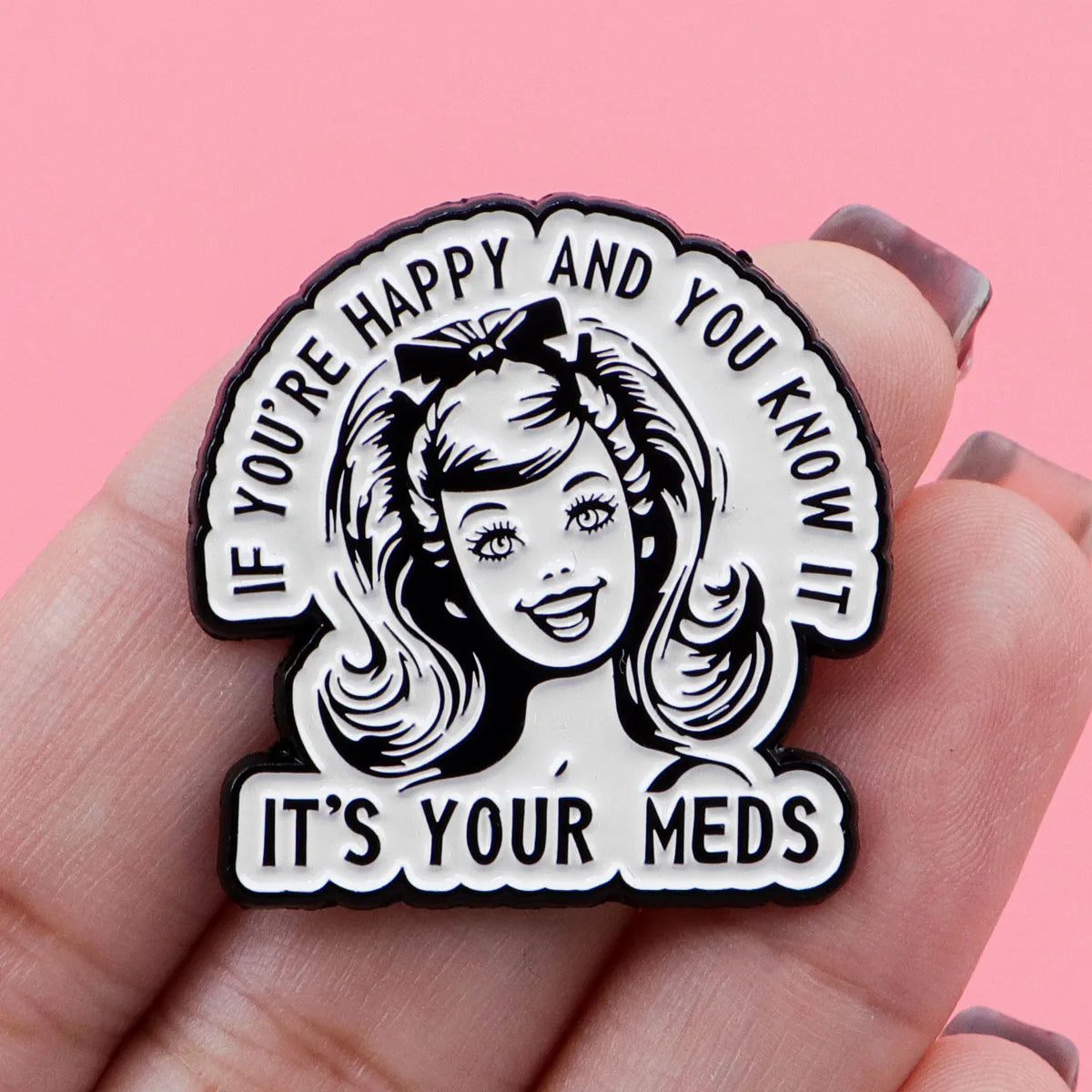 A black enamel pin featuring a smiling woman's face and the text If you're happy and you know it's your meds
