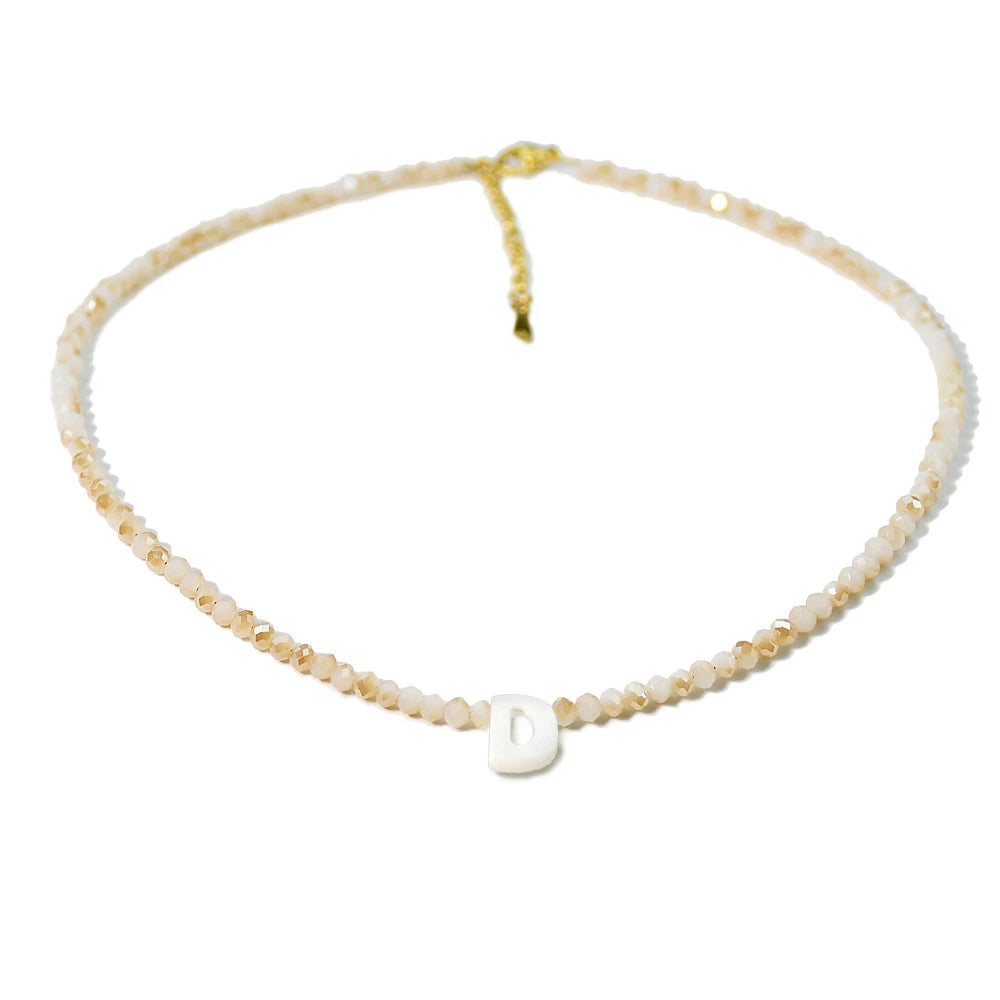A delicate necklace made of mother of pearl beads with crystal accents and a diamond initial charm.