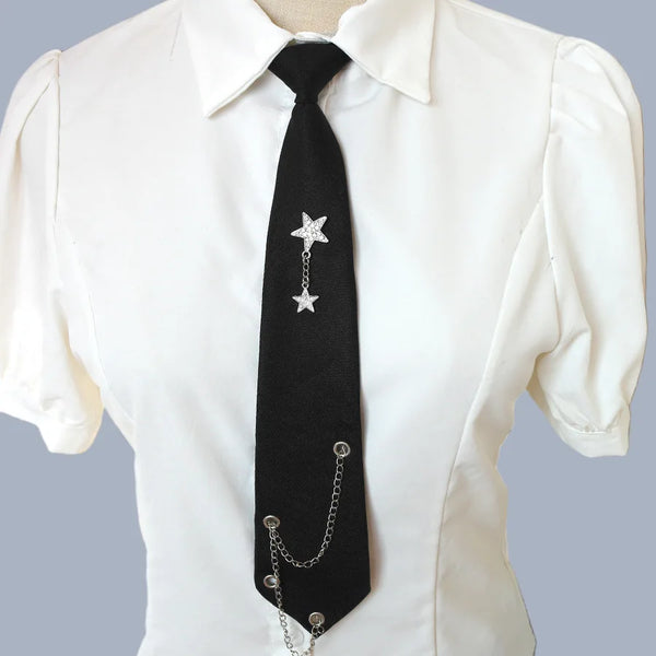 Black tie with a silver star pendant and chain worn under a white collared shirt.