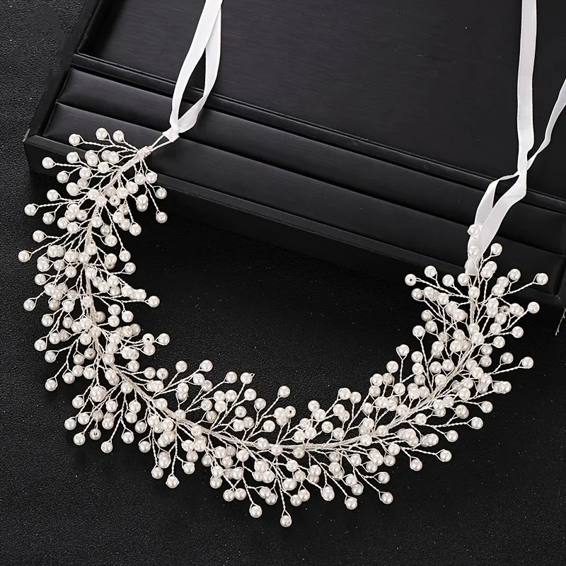 Elegant pearl hair vine headband with white ribbon displayed on a black surface.