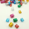 A collection of multicolor dreadlock hair rings in various metallic and plastic finishes scattered on a white background.