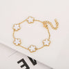 Pulsera de acero inoxidable chapada en oro con pequeños charms de flores blancas en una cadena dorada.