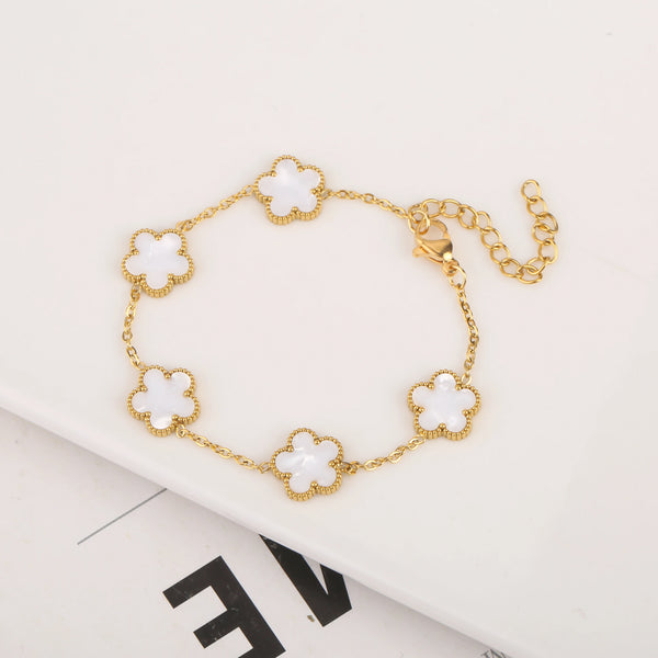 Gold plated stainless steel bracelet featuring small white flower charms on a gold chain.