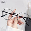 A hand is holding a pair of black anti-blue light metal eyeglasses against a white background.