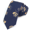 Cravate en coton bleu marine avec imprimé floral or, pliée et présentée.