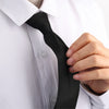 A hand is adjusting a black clip-on security tie on a white dress shirt.