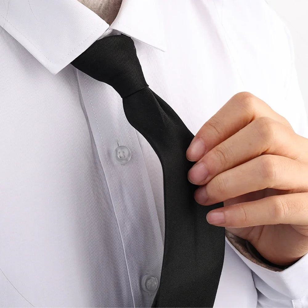 A hand is adjusting a black clip-on security tie on a white dress shirt.