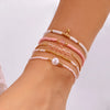 A stack of bohemian pearl beaded bracelets in shades of pink and white worn on a wrist.