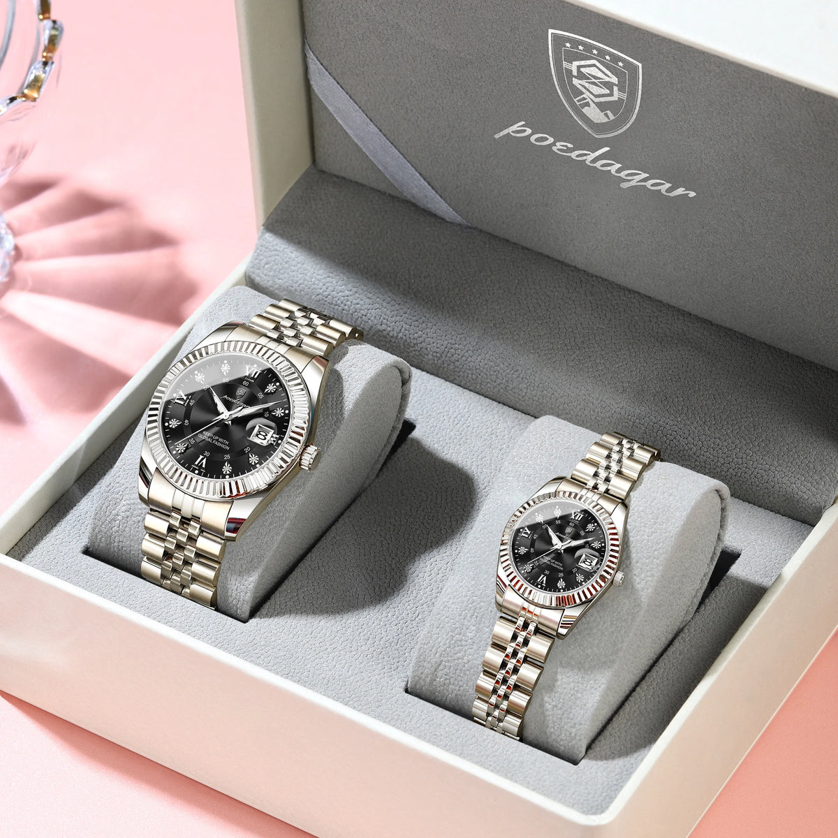 A pair of matching couple watches with luminous hands and date display are displayed in a box.