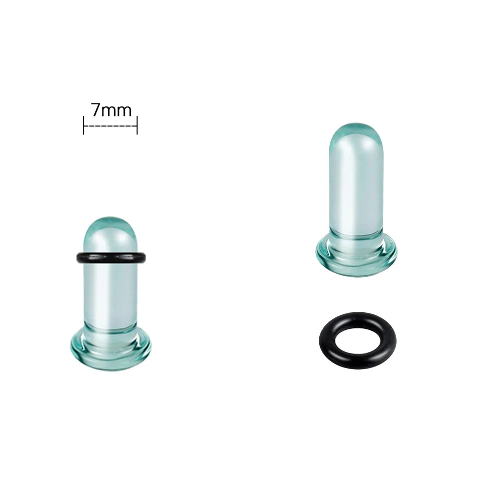 A glass ear stretching kit showing a cylindrical plug and a black ring.