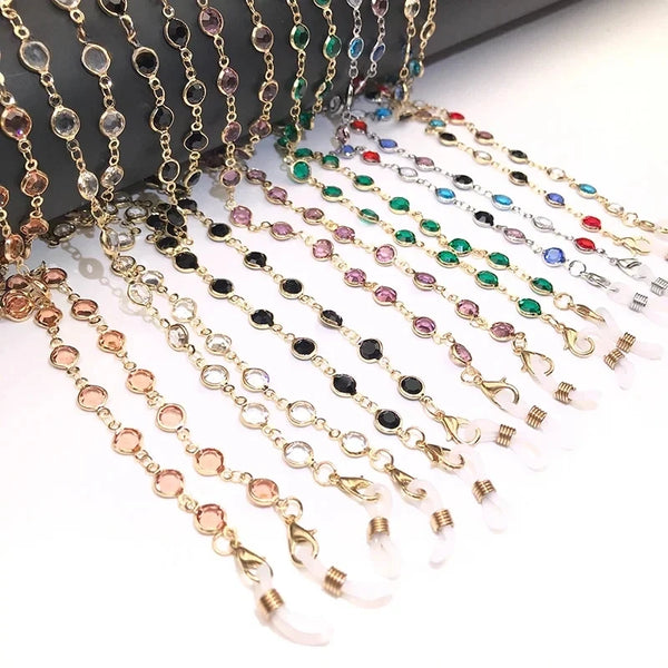 A collection of colorful crystal bead eyeglass chains for women displayed on a dark surface.
