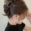 A woman is shown tying up her dark brown hair in a messy bun using square lightweight hair claw clips.