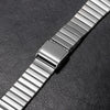 Nahaufnahme eines Edelstahlarmbandes mit Metallverschluss auf einer dunklen Oberfläche.
