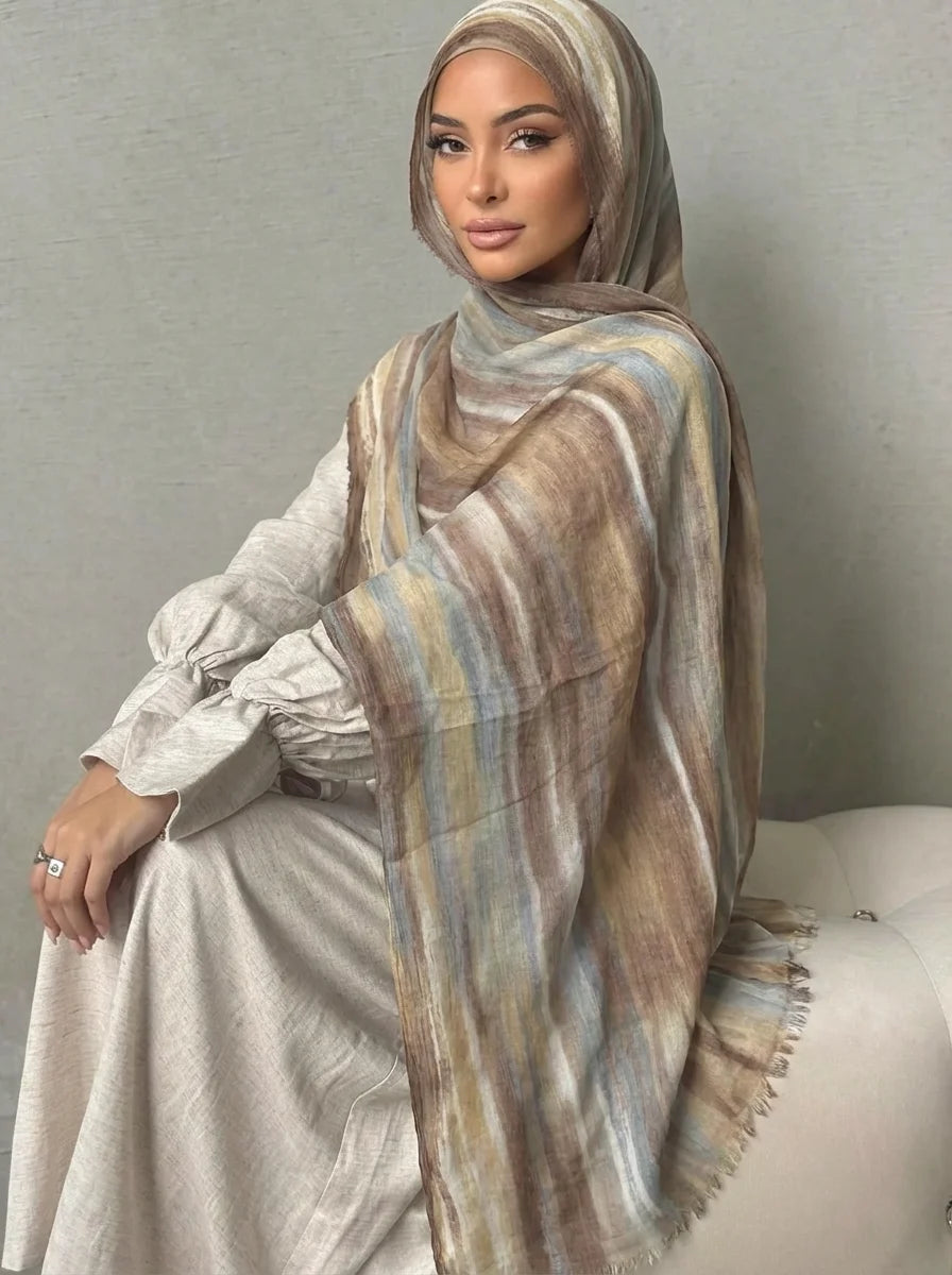 Una mujer vistiendo un elegante pañuelo de hijab a rayas beige y marrón sobre su hombro.