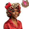 A woman wearing a leopard print hair drying cap with red floral accents and a red satin shirt.