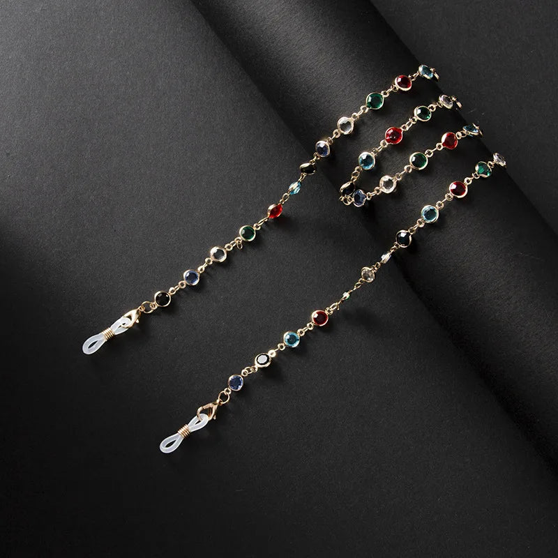 Una delicada cadena de oro con cuentas de cristal de varios colores, mostrada contra un fondo oscuro.