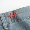 A pair of red star-shaped decorative waist buckle buttons attached to a denim fabric.