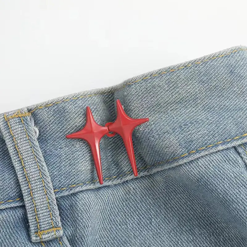 A pair of red star-shaped decorative waist buckle buttons attached to a denim fabric.