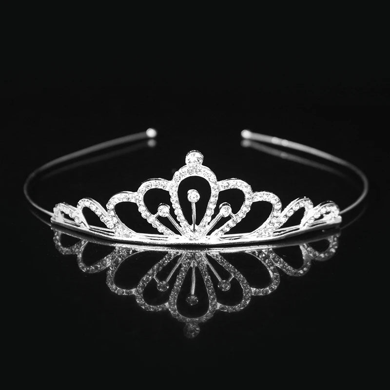 Tiara y corona de princesa de cristal brillante en el cabello reflejada en una superficie oscura.
