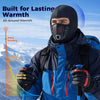 A man wearing a black balaclava face mask and blue outdoor jacket is shown in a snowy mountain landscape.