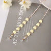 A delicate gold and pearl beaded eyewear chain necklace displayed on a gray background.