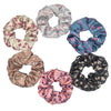 Un set de seis gomas de tela con estampado floral de satén en varios tonos de rosa, azul y gris.