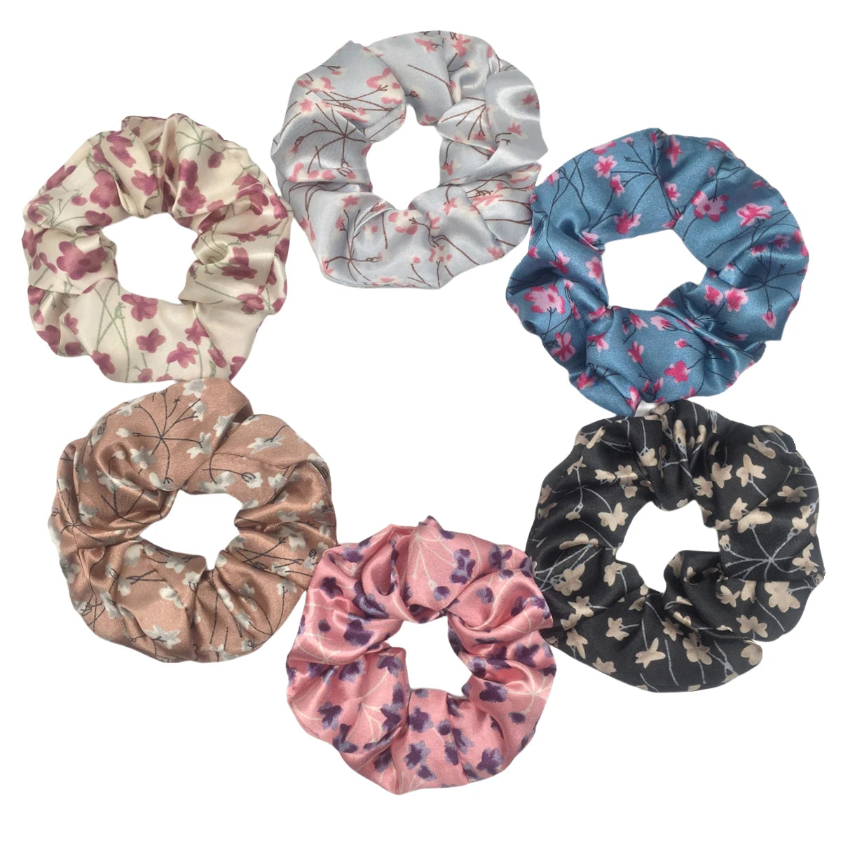 Un set de seis gomas de tela con estampado floral de satén en varios tonos de rosa, azul y gris.
