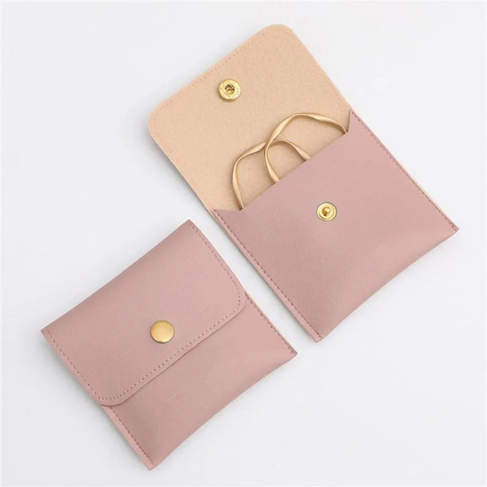 A light pink PU leather jewelry pouch with a snap button closure and a gold-colored cord.