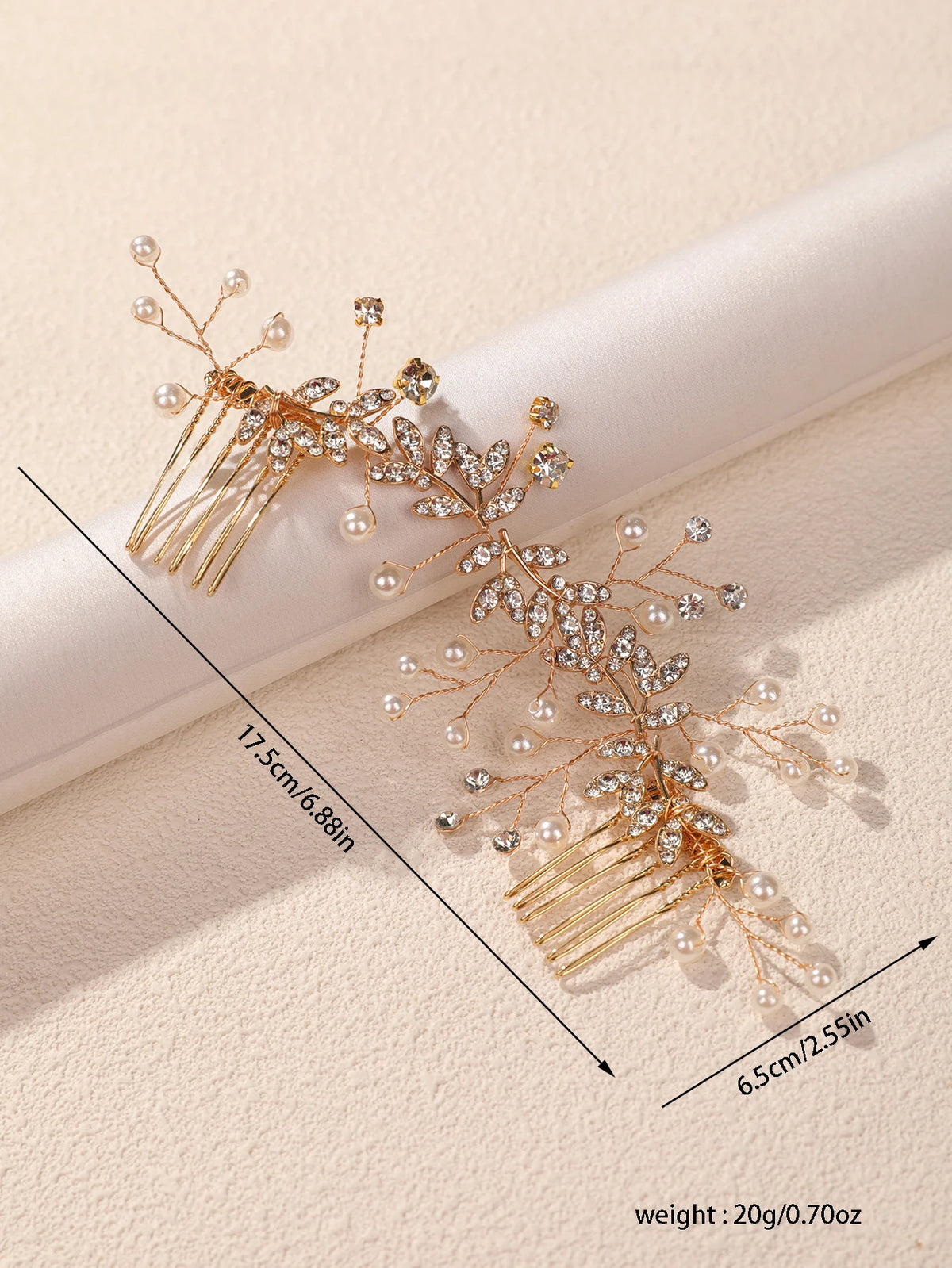 A delicate gold leafed crystal hair comb with pearl accents shown against a light background.