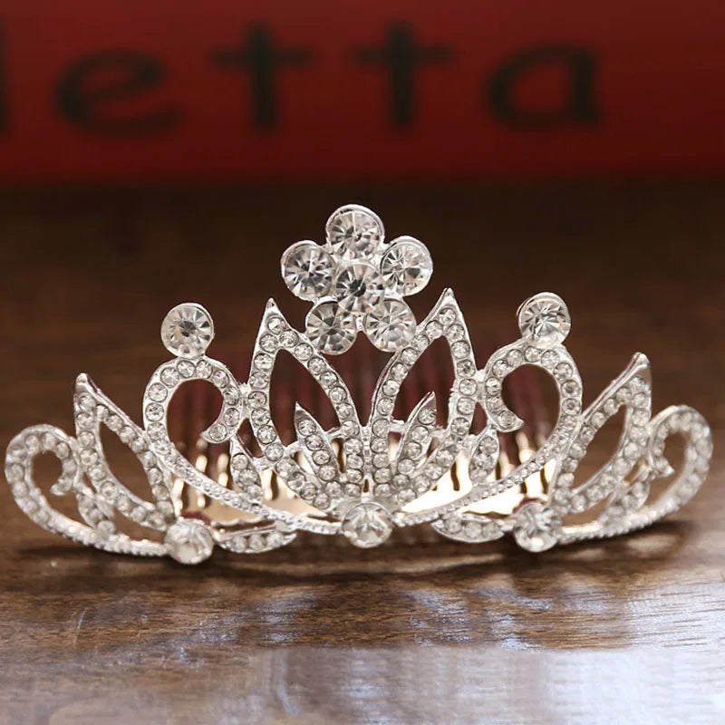 A sparkling crystal princess tiara hair comb for women displayed on a wooden surface.
