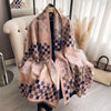 A pink and blue checkered cashmere feel scarf draped over a dark garment, displayed in bright natural light.