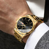 A close-up of a gold-toned stainless steel quartz watch worn on a wrist, paired with a white shirt and a textured suit sleeve