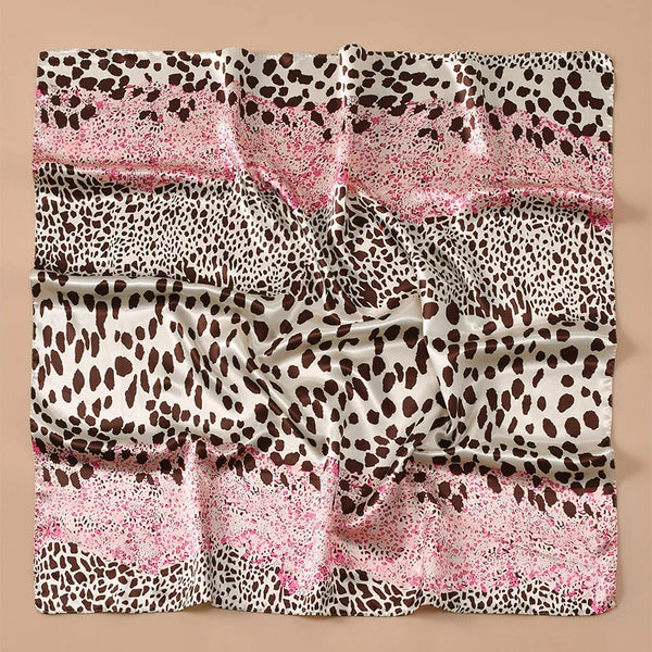 A square satin scarf featuring a leopard print pattern in shades of pink, brown, and white.