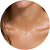 A close-up of a gold plated alphabet initial necklace worn around the neck.