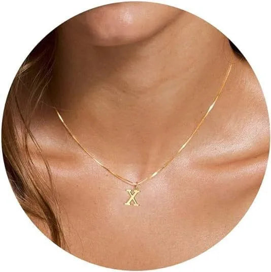 A close-up of a gold plated alphabet initial necklace worn around the neck.