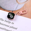 A pink LED digital keychain watch with a black face is clipped to a white paper.