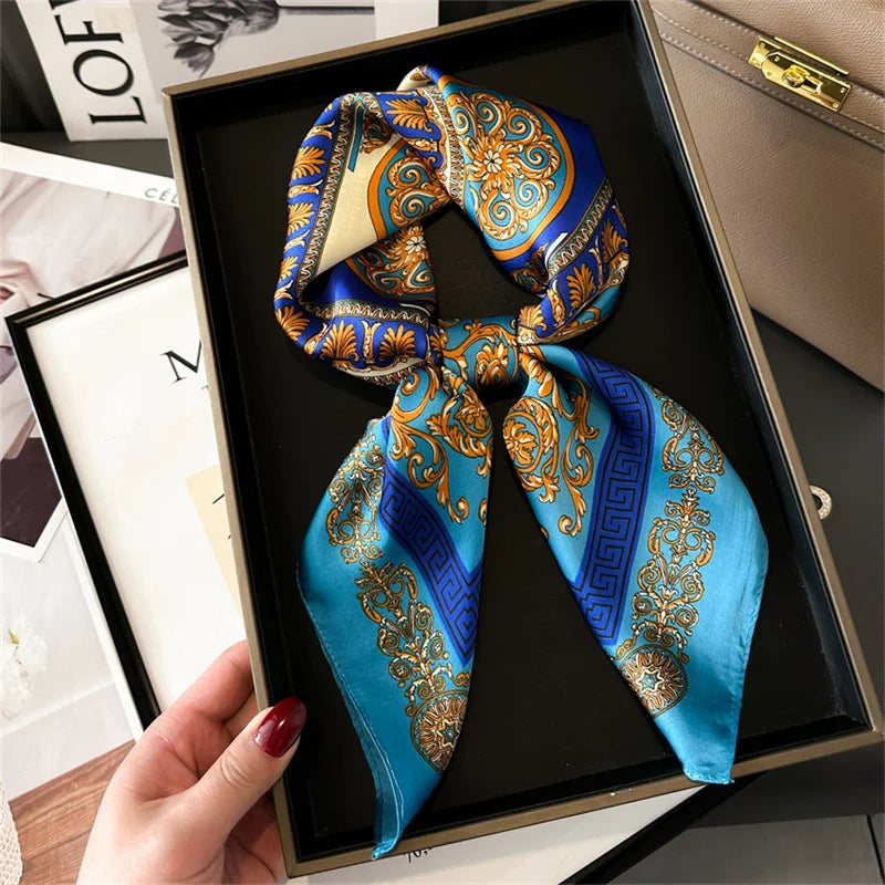 A blue and gold silk scarf tied in a bow displayed in a black box.