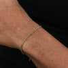 A close-up of a man's wrist wearing a gold-toned stainless steel Cuban link bracelet.
