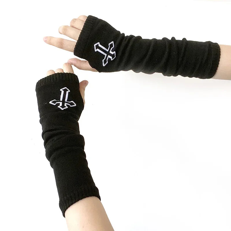 Black knitted fingerless gloves with a white cross design worn on a hand and arm.