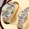 A pair of silver stainless steel quartz watches are displayed on a light-colored surface.