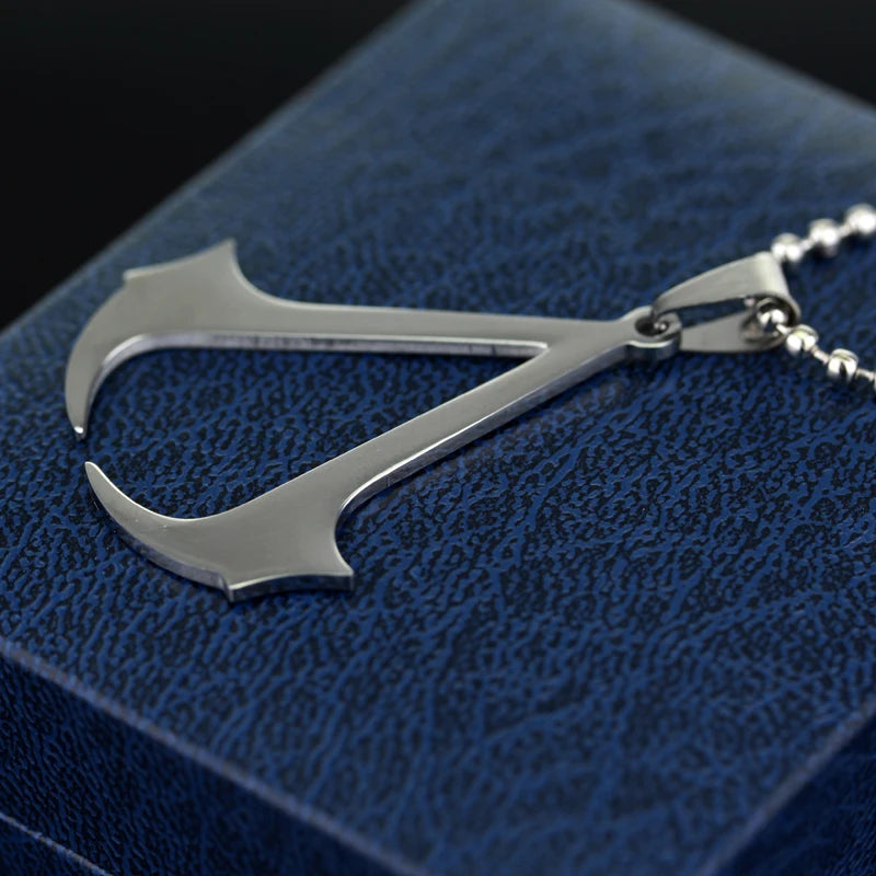 A stainless steel pendant necklace shaped like a dagger is displayed on a dark blue fabric background.