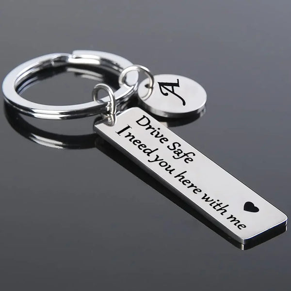 Clé USB argentée avec une initiale A et une plaque gravée : Conduis prudemment, j'ai besoin de toi.