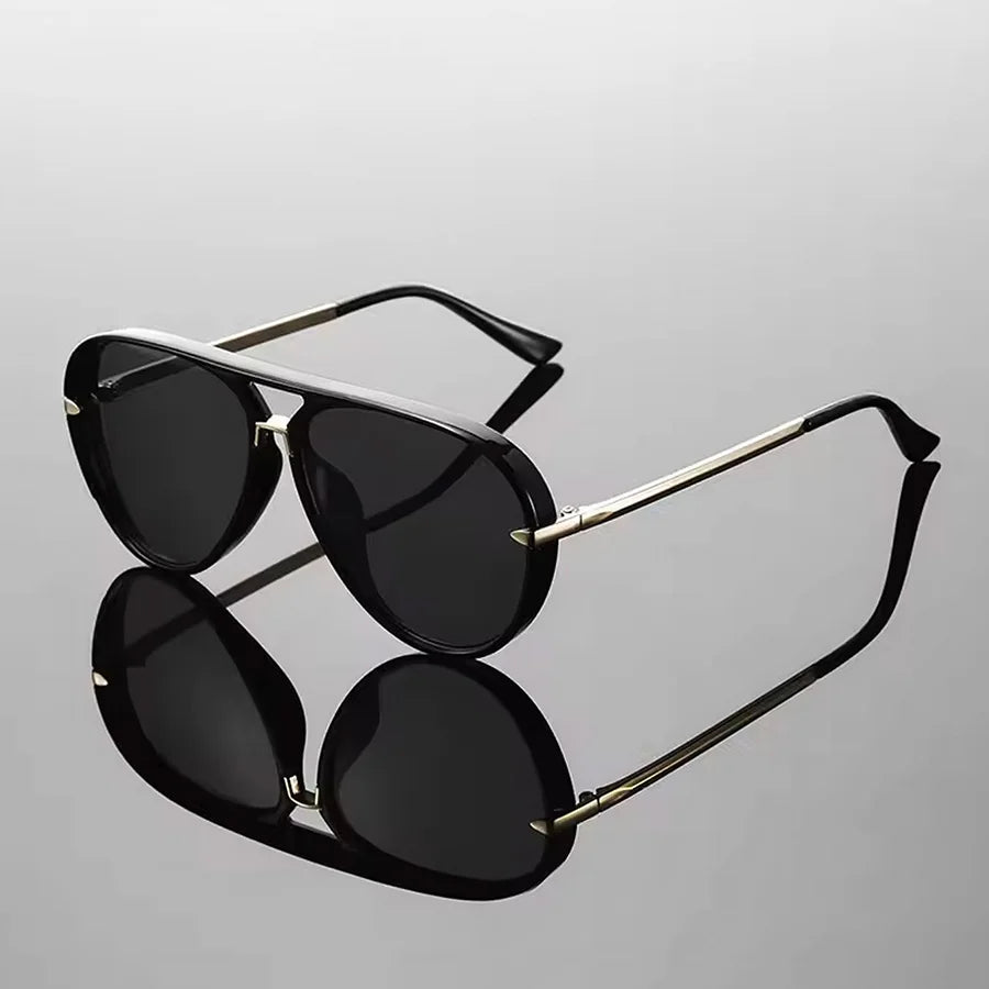 A pair of retro large frame green fashion sunglasses with gold-toned arms against a light gray background.