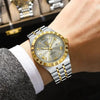 A close-up of a men's luminous quartz wristwatch with a gold-toned case and silver bracelet on a wrist.
