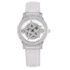 A white leather strap watch with a diamond-encrusted bezel and a geometric face design.