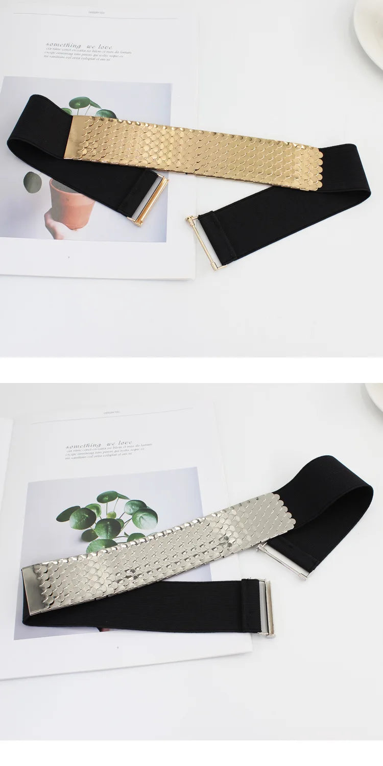 Gros plan d'un large ceinture élastique noire avec un accent texturé doré, présentée à côté d'un morceau de papier.