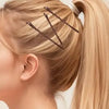 A close-up of a blonde ponytail being styled with brown hair and clear bobby pins.
