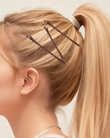 A close-up of a blonde ponytail being styled with brown hair and clear bobby pins.