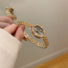 A hand is holding a gold-toned quartz fashion wristwatch with a mesh bracelet and clear crystal face.